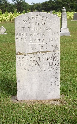 White tombstone in church cemetery reading Harriett wife of T Thomas .
