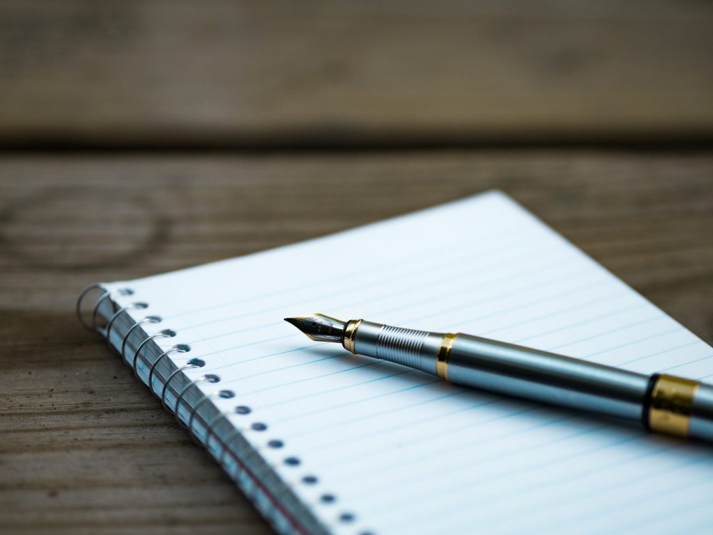 spiral notebook with silver fountain pen for research