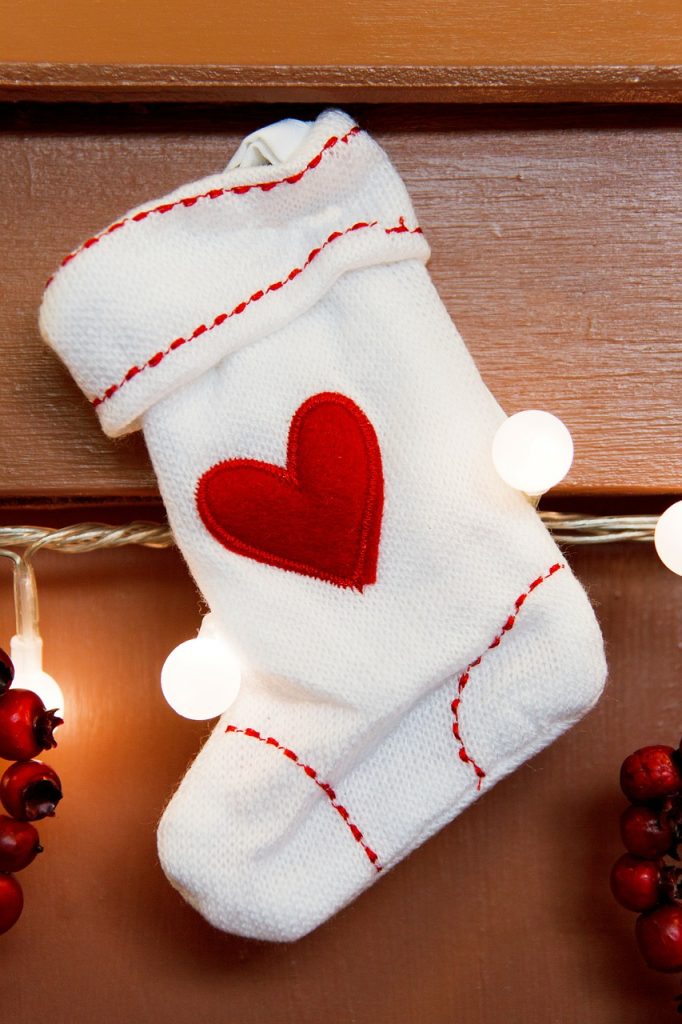 Small white Christmas stocking with red stitch trim and red heart.
