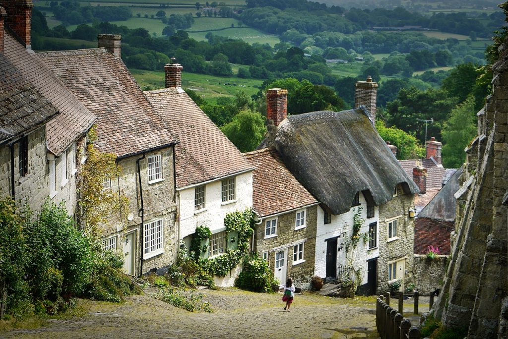 Cobblestone road in UK village with attached homes and vines growing on walls