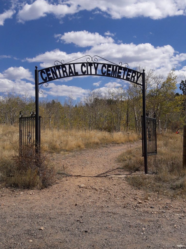 Central City Cemetery Entrance metal gate with dirt road leading into it.