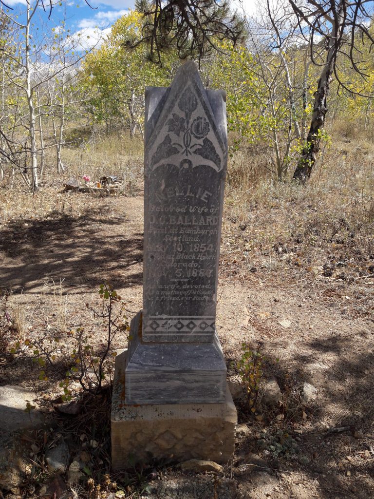 vertical tombstone for Nellie, beloved wife of D. O. Ballard. Gravetone in old cemetery among Ash trees with yellow leaves.