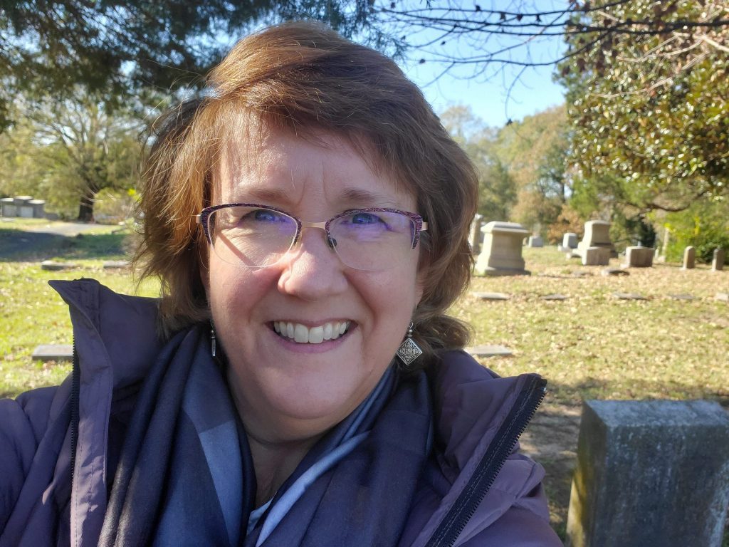 Lisa Lisson - woman with glasses and brown hair - taking selfie in a cemetery.