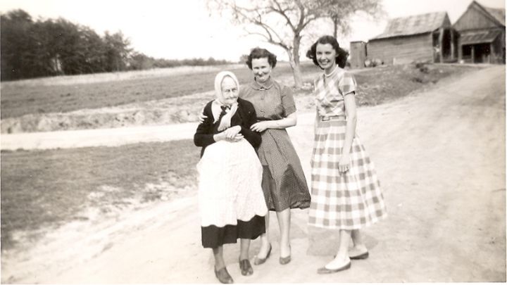 black and white photo of one elderly woman and 2 younger women