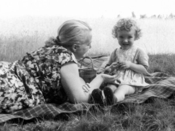Black and white phots of adult woman laying on grass talking to a young child