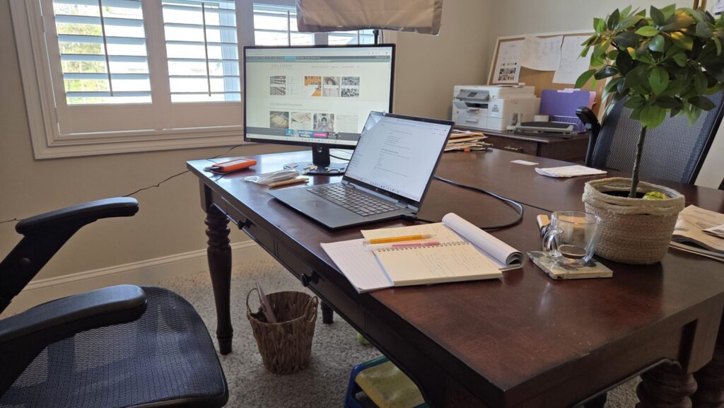Office desk with laptop, second computer monitor and paper and pens
